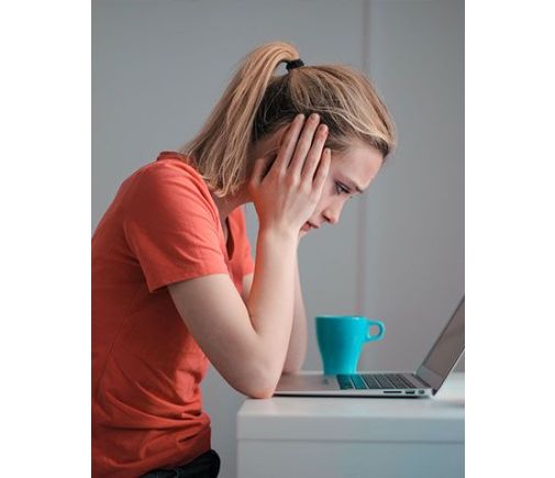 Woman hunched over her laptop, looking unhappy.