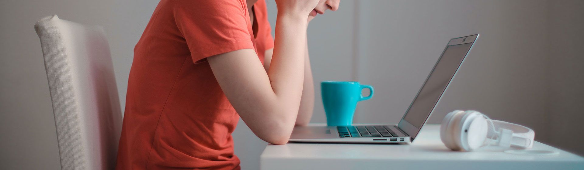 Woman hunched over her laptop, looking unhappy.